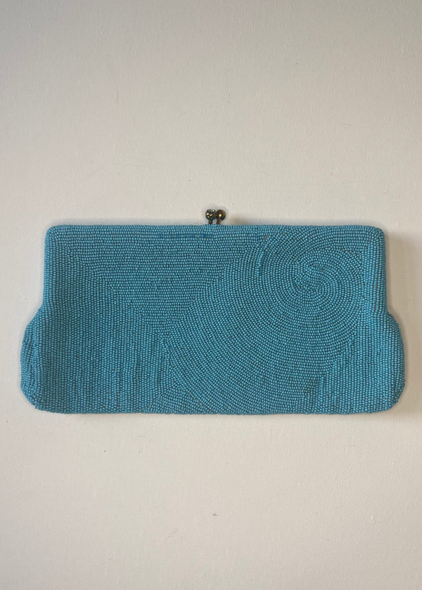 Blue beaded clutch bag on a light gray background